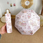 Cartoon cat -themed umbrella and case held by a hand on a wooden floor.