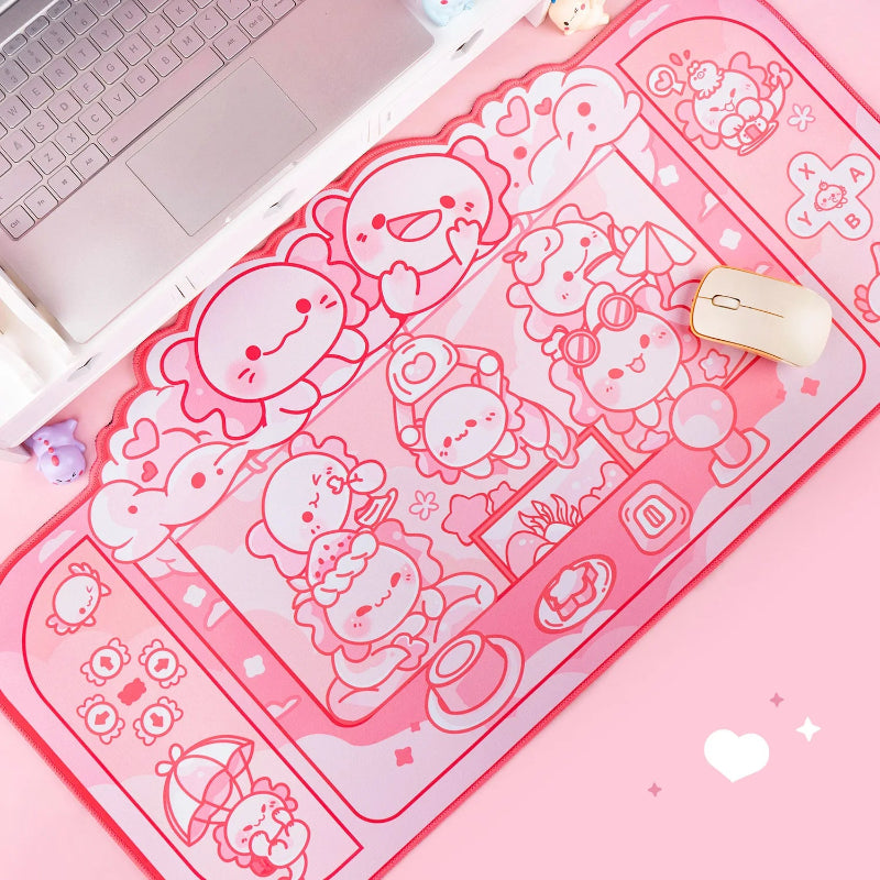 Pink desk mat with cartoon axolotl design on a desk with a laptop and mouse.
