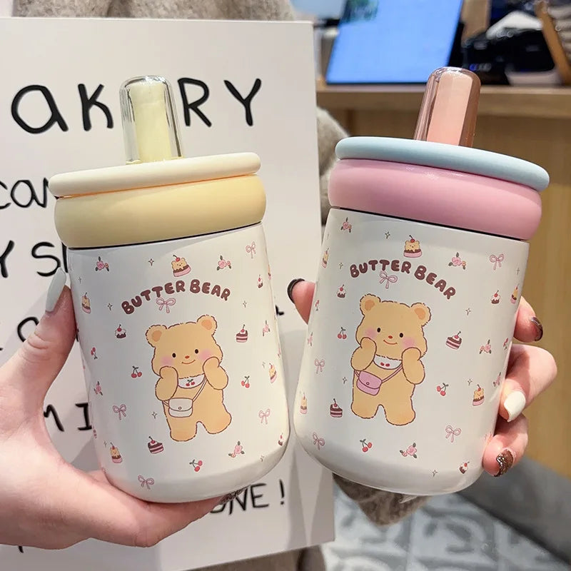 Two cute bear-themed cups with colorful lids held by a person.