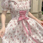 White floral dress with pink ribbon and bow details.