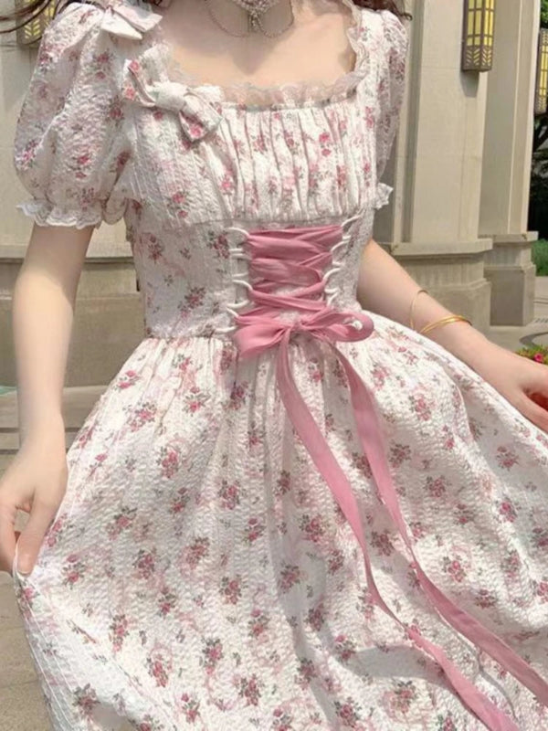 White floral dress with pink ribbon and bow details.