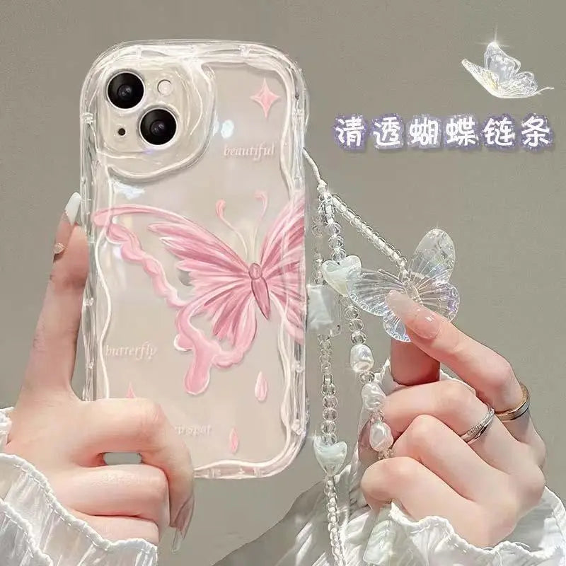 Phone case with butterfly design held by a person, featuring a decorative chain. the butterfly on the case is a subtle pink.