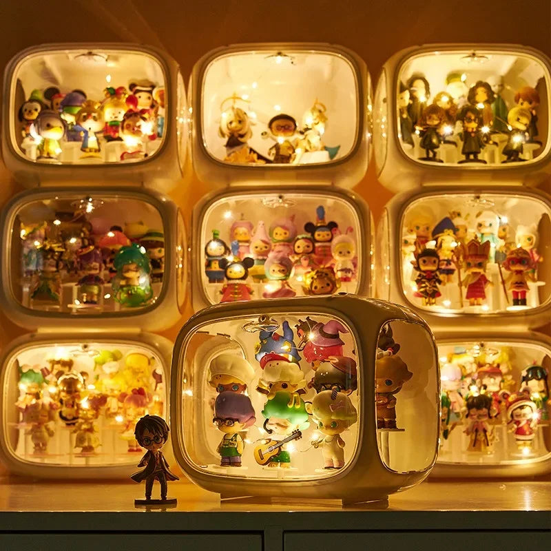 A collection of retro-style glowing display boxes containing many small colorful figurines, arranged on a shelf. The boxes are illuminated from within, creating a warm golden glow, with one larger box in front and smaller boxes behind it.
