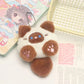 Plush keychain shaped like a cute animal with a background of stationery items.