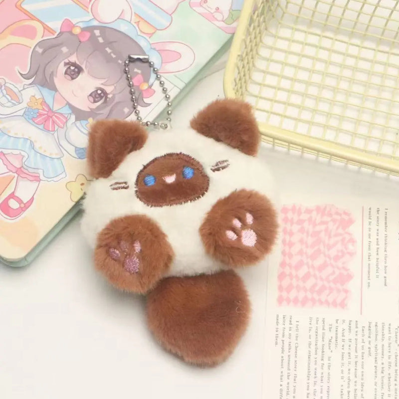 Plush keychain shaped like a cute animal with a background of stationery items.