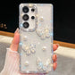 Phone case with butterfly and pearl designs held by a hand, case is white