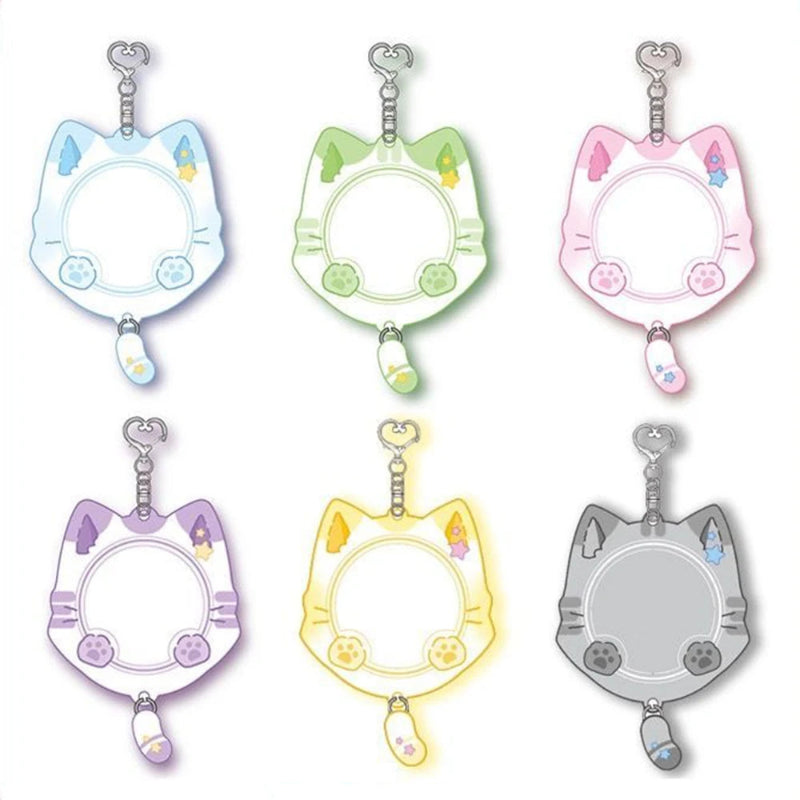 Six cat-head keychains or charms shown in different pastel and neutral colors on a plain white background. Each has a silver metal clasp at the top and a small dangling charm at the bottom.