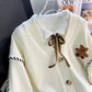 Sweet Teddy Bear Cardigan white edition with a bear sown into the chest area whilst the sleeves have large black stitches where they have been joined and black strips on the wrist cuffs and black and white trim.  this is a close up image of the product focusing on the buttons and craftsmanship. 