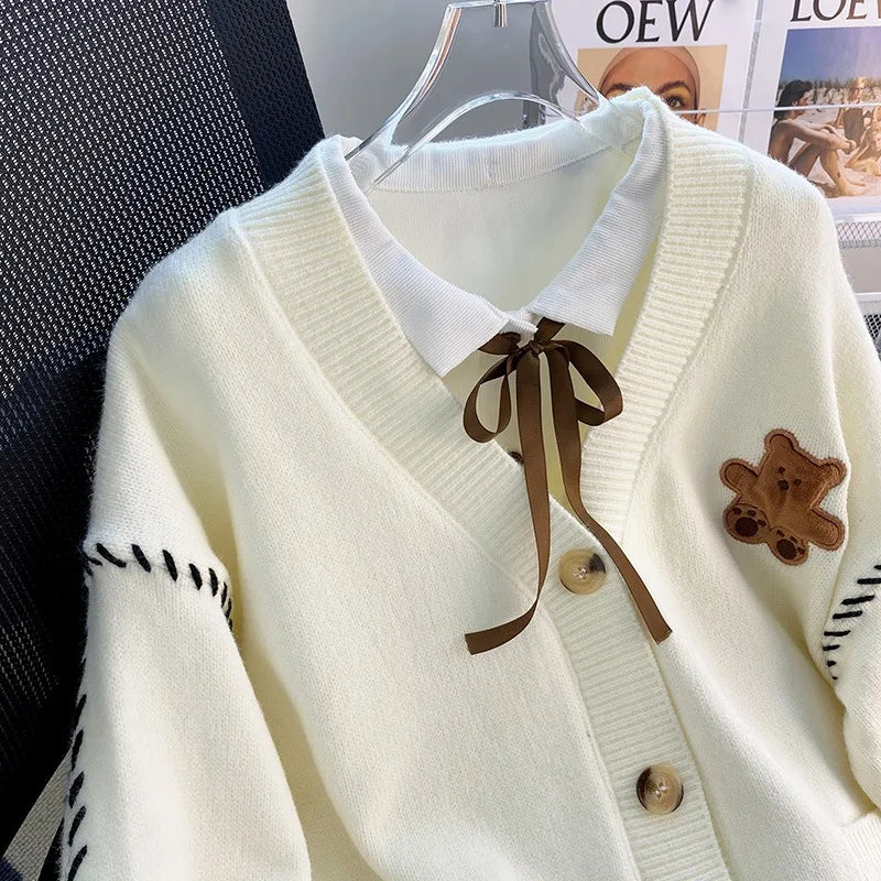 Sweet Teddy Bear Cardigan white edition with a bear sown into the chest area whilst the sleeves have large black stitches where they have been joined and black strips on the wrist cuffs and black and white trim.  this is a close up image of the product focusing on the buttons and craftsmanship. 