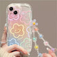 Clear phone case with floral designs and a strap held by a person.