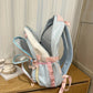 Light blue and pink backpack on a wooden surface with a neutral background