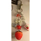 Strawberry-themed keychain with heart and bow charms on a beige background