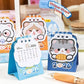 Set of kawaii cat-themed desk calendars with a pen on a surface.