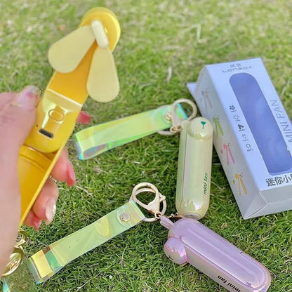 Colorful mini fans on a grassy background with packaging.