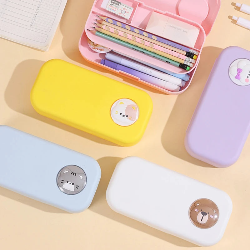 Colorful pencil cases with cartoon bear faces on a beige surface