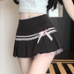Black pinstripe skirt with a white top and pink ribbon worn by a person.