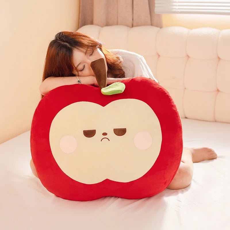 Person lying on a bed with a large red apple-shaped pillow
