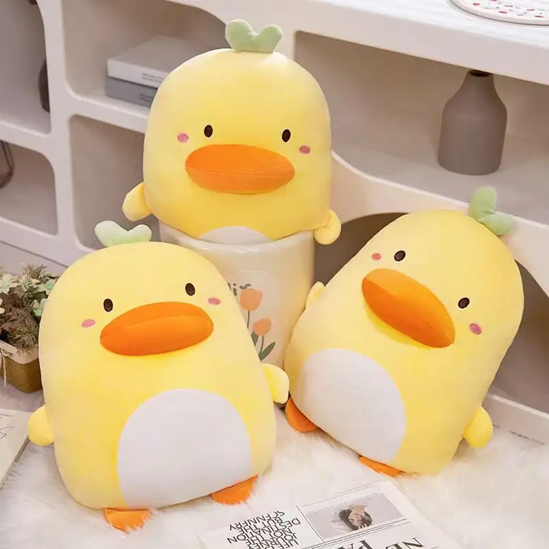 Kawaii Derpy Duck Plushies displayed on a white desk surface , with one sat in a plant pot.