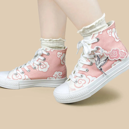 Pink high-top canvas sneakers with white cloud patterns, white laces, and a white ruffled sock worn on a person's feet, set against a solid beige background.
