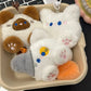 Three plush keychains shaped like animals in a cardboard box.