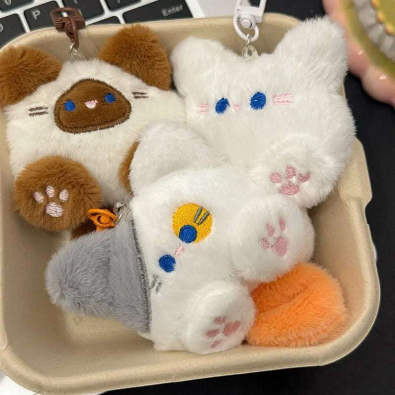 Three plush keychains shaped like animals in a cardboard box.