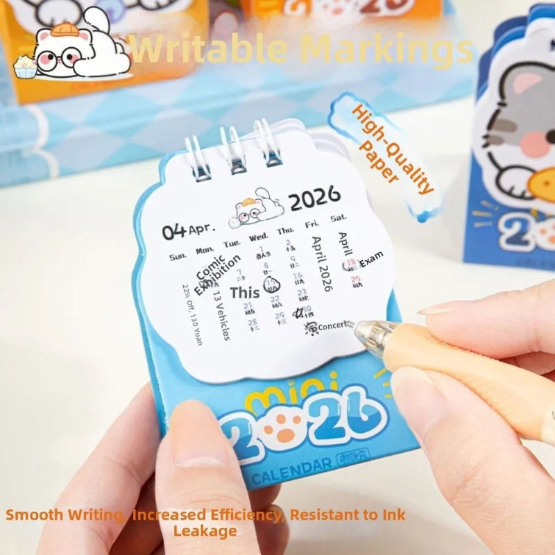 Small calendar with a kawaii design, held by a hand with a pen, on a light background.
