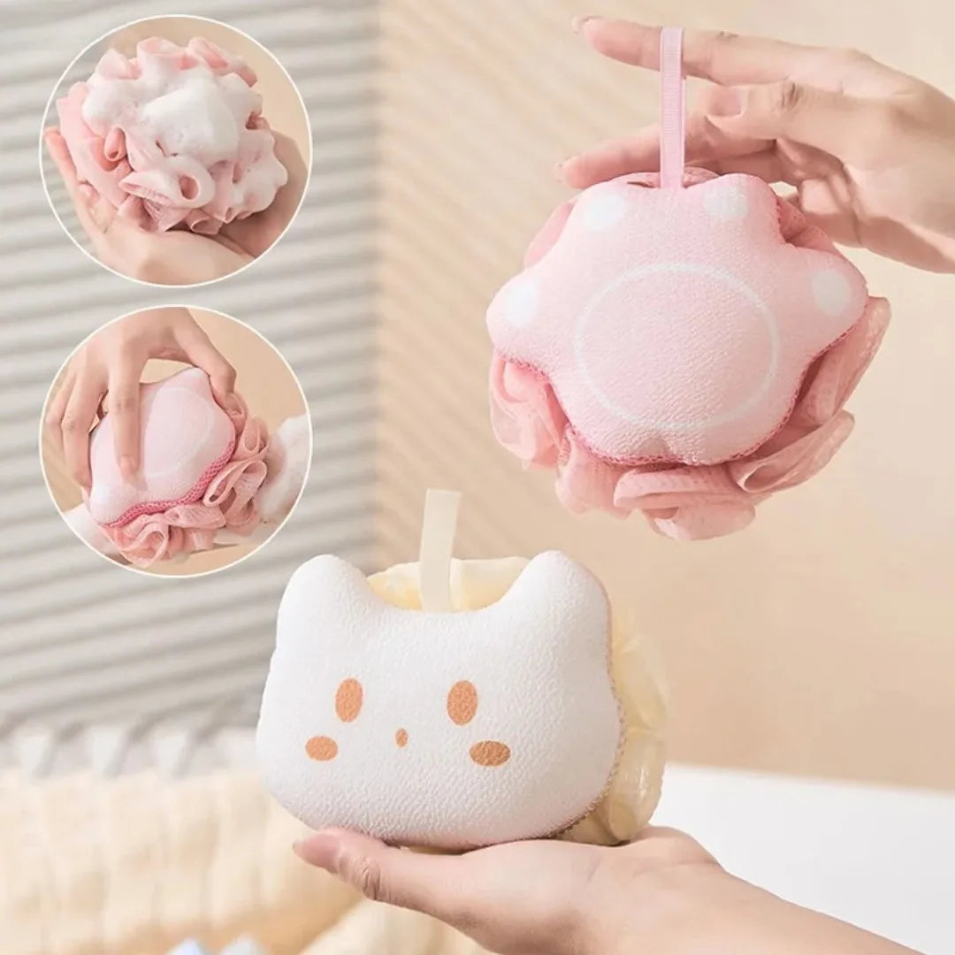 Pink cat-shaped sponge with a hand holding it, set against a neutral background.