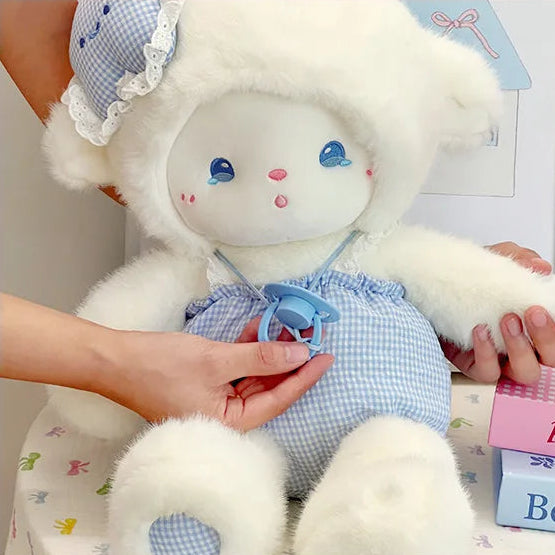 White lamb stuffed animal with blue checkered outfit held by a person.