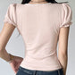 Person wearing a light pink top with ruffled sleeves and blue jeans on a plain background