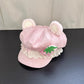 Pink kawaii hat with bear ears and lace details on a dark surface