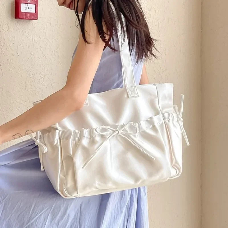 Woman holding a white tote bag against a plain background