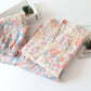 Floral-patterned fabric on a white surface with a cactus and books in the background