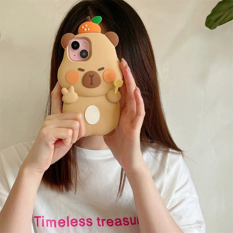 Person holding a cute capybara phone case with an orange on its head.