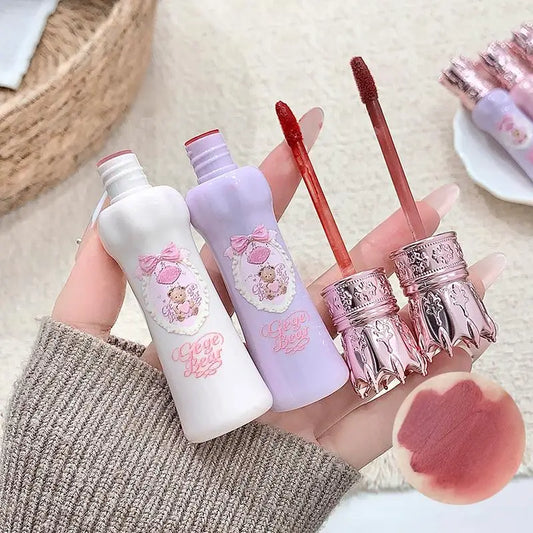 Lip gloss set with decorative packaging held by a person, on a neutral background.