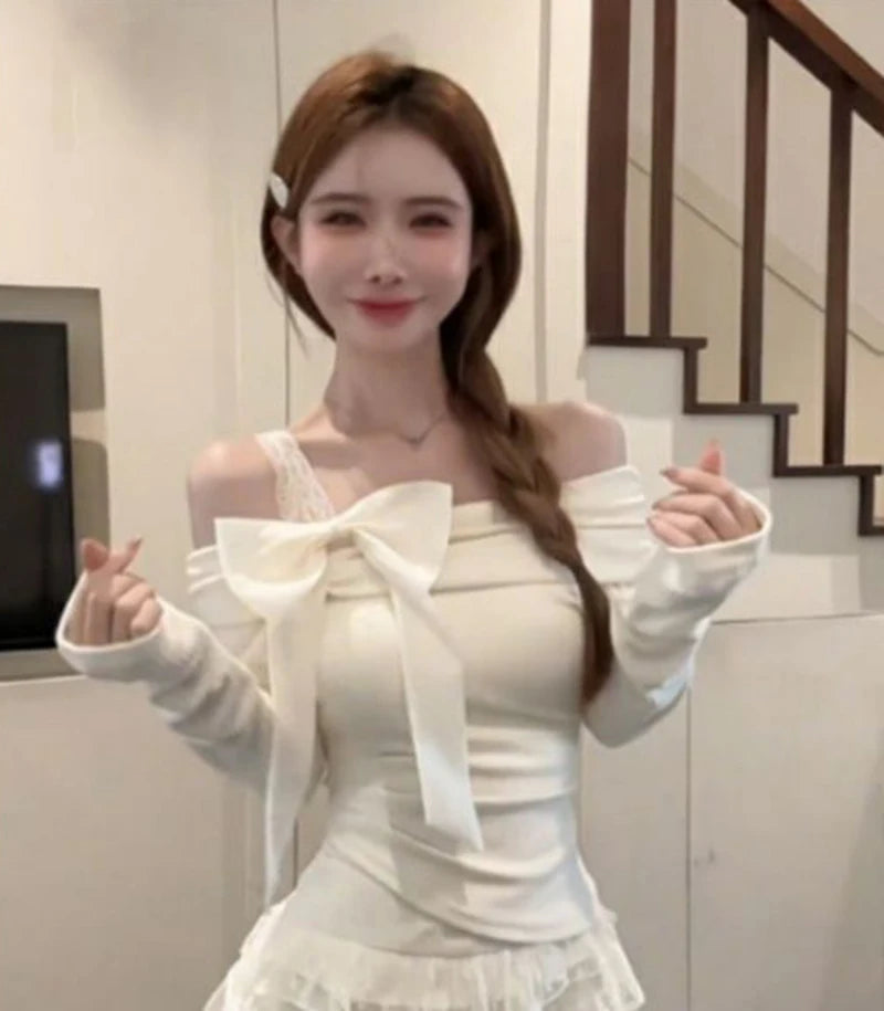 Woman wearing a white off shoulder long sleeved shirt with a lacy strap and a white skirt