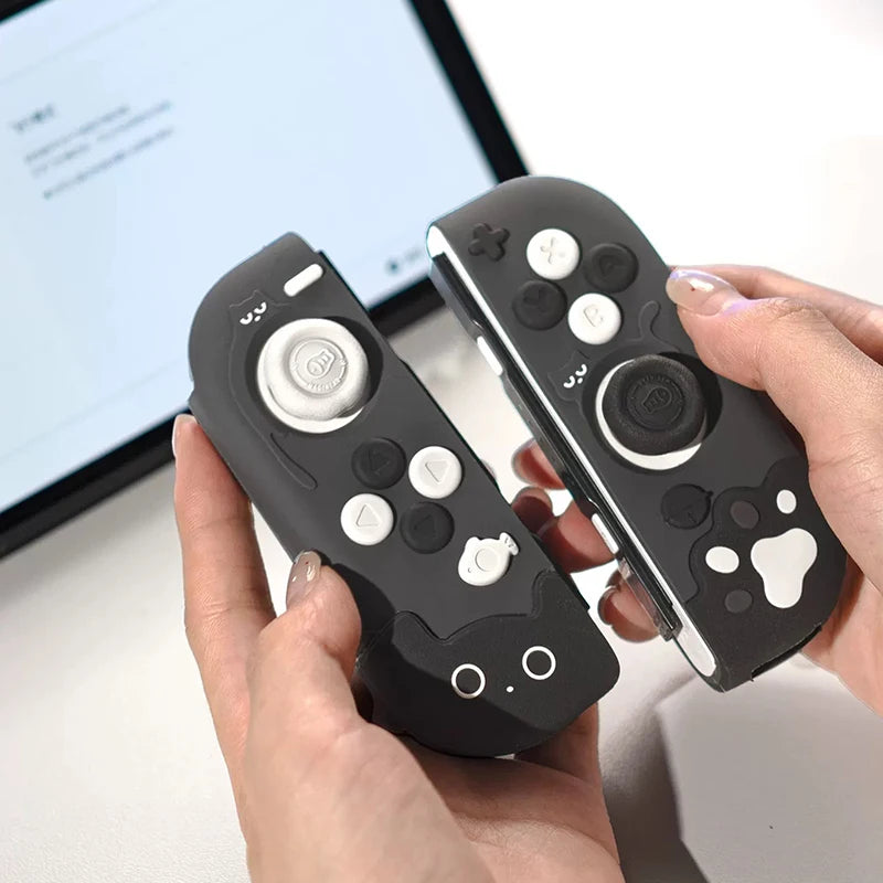 Black gaming controllers with cartoon face designs held by a person in front of a computer screen.