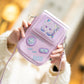 Hand holding a pink game console-shaped bag with a blurred background