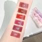 Lipstick swatches on a person's arm with numbered labels, next to pink and white lip gloss .
