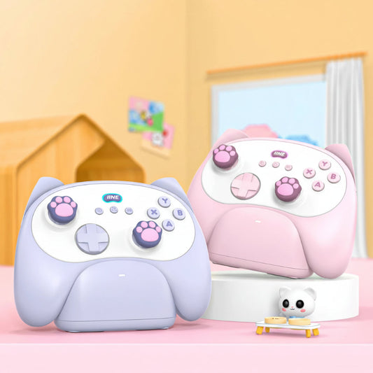 Two cat-shaped controllers with a charging dock on a pink surface.