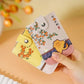 A hand holding two small decorative card cases or wallet-style phone cases with snap closures. One case is pale pink with orange fruit illustrations and a small character print, and the other is pale yellow with similar orange fruit illustrations.
