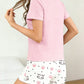 Woman wearing a pink top and white skirt with kawaii cat print on a light background
