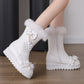 White winter boots with fluffy details on a wooden floor.