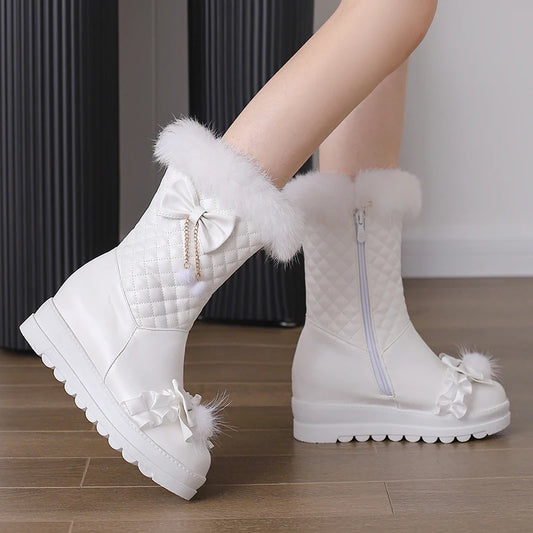 White winter boots with fluffy details on a wooden floor.
