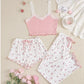 Pink lace top and floral pajama set on a beige surface with pink flowers.