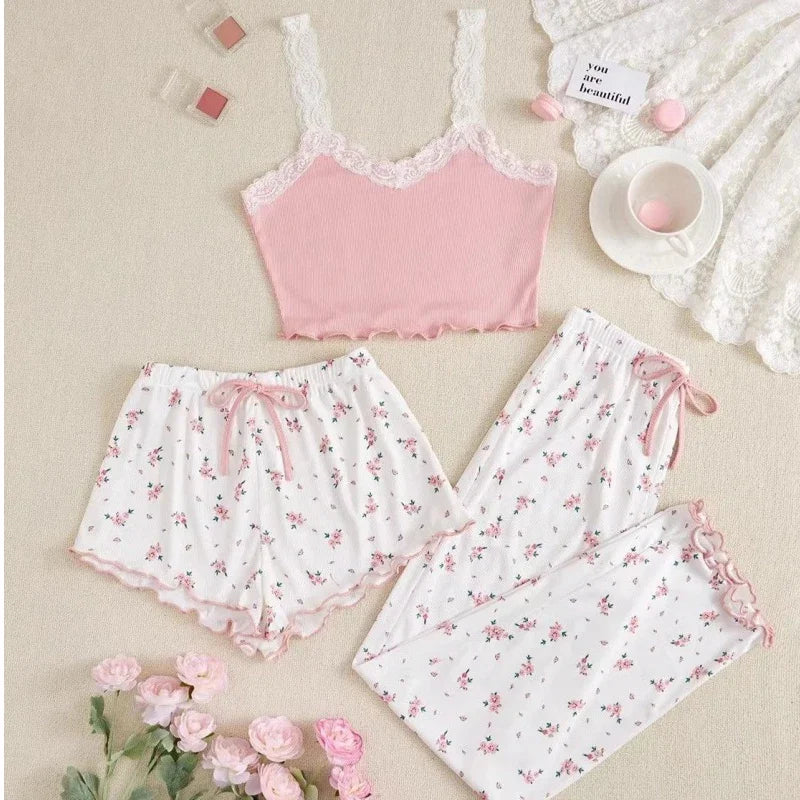 Pink lace top and floral pajama set on a beige surface with pink flowers.