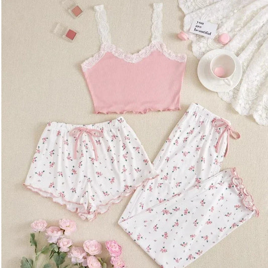 Pink lace top and floral pajama set on a beige surface with pink flowers.