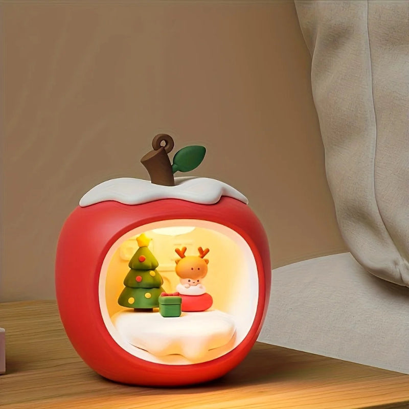 Decorative apple-shaped lamp with a small scene inside on a wooden surface.