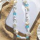 Mermaid treasure cute phone charm bracelet displayed on sandy beach