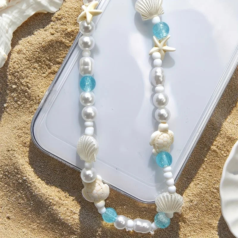 Mermaid treasure cute phone charm bracelet displayed on sandy beach