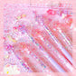 Decorative pens with glittery accents on a pink background